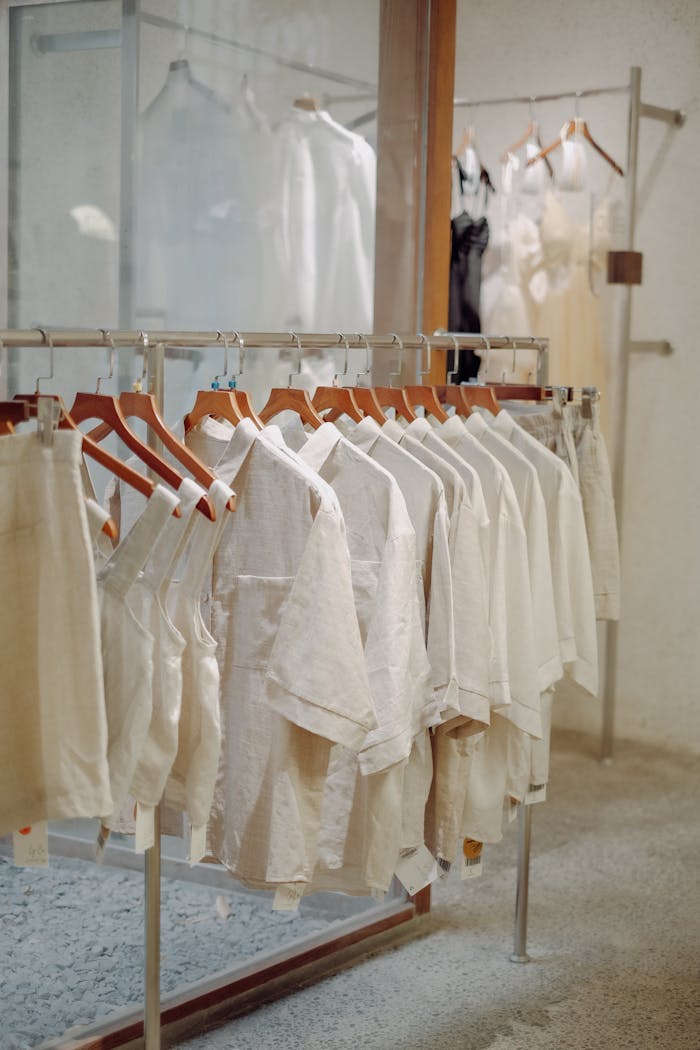 Modern clothing store with neutral-colored garments arranged on hanging racks.