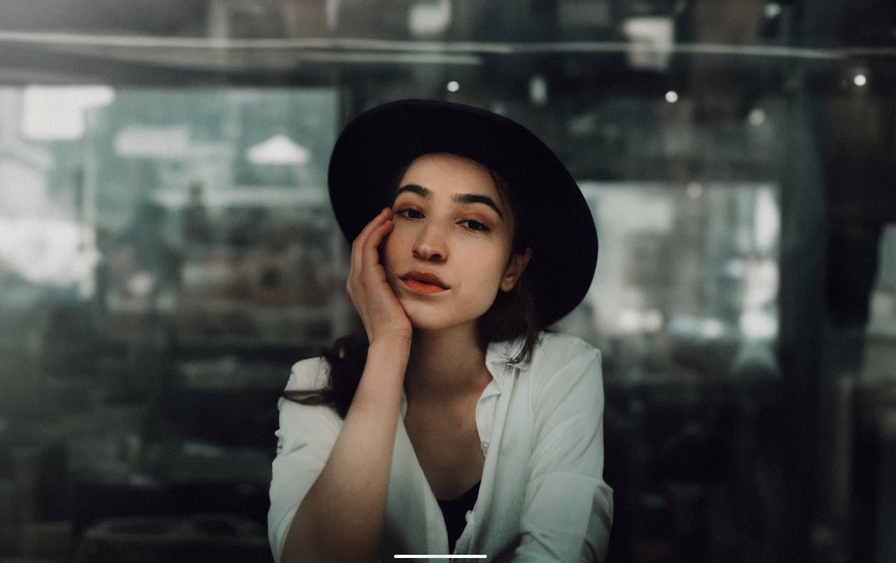 Portrait of a woman wearing a hat, posing thoughtfully in a cozy café in Istanbul.